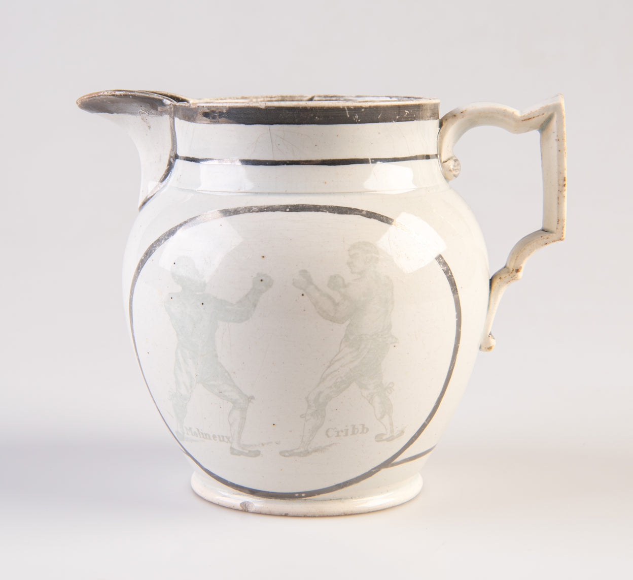 [Pearlware jug decorated with transfer image of Tom Molineux and Tom Cribb facing each other in a boxing match, a verse to the other side.]